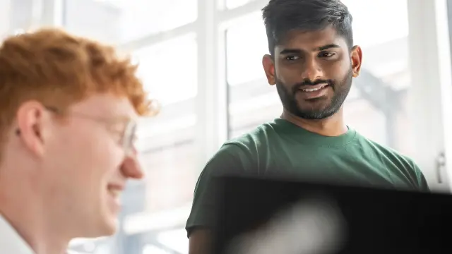 Zwei Kollegen, die in einem hellen Büro zusammenarbeiten – Das spiegelt die Teamarbeit wider, die hinter den Leiterplatten-Lösungen von copperdot steht, die die Beschaffung für copperdot-Kunden dank der Innovation und Zuverlässigkeit von Bosch wesentlich erleichtern.