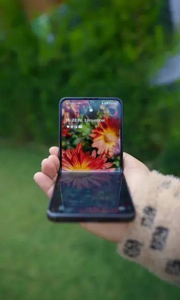 A woman is holding her bendable phone in the garden and demonstrates that such bendable modern devices require flexible PCB solutions by copperdot.