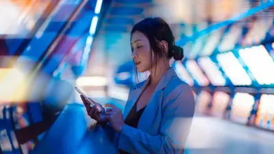 Eine Frau nutzt ihr Smartphone in einer futuristischen, beleuchteten Umgebung – ein Symbol für digitale Vernetzung und Innovation durch Leiterplattentechnologie beschaffen durch copperdot.