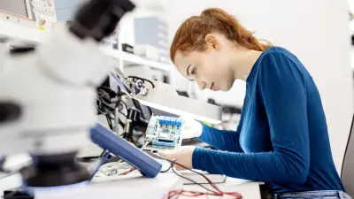 Eine junge Frau in einem Labor verwendet die entwickelten unbestückten Leiterplatten nach IPC-Norm, die für einen OEM-Kunden von Bosch copperdot, bestückt werden sollen.