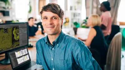 Engineer smiling at the camera with PCB design software on the screen, illustrating the use of DFM principles at copperdot for design for manufacturing